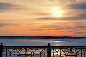 Beautiful sunset on the dark blue evening sky reflected on the river ice, winter landscape