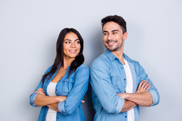 Portrait of caucasion cute hispanic couple - man with bristle and pretty, cute woman with crossed hands standing half turned and looking to each other over grey background - obrazy, fototapety, plakaty