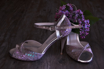 Argentine tango stilettos and lilac flower on dark wood