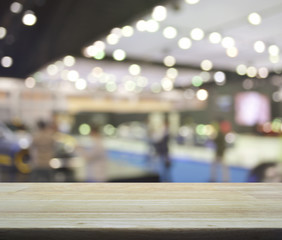 Empty wooden table over defocused light and shadow of shopping mall