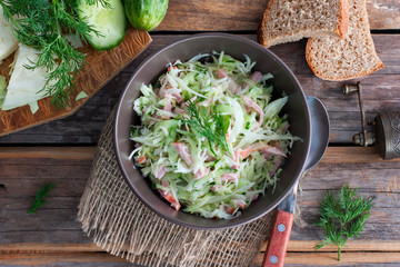 prepared salad with cabbage and ham on a wooden table, top view, horizontal