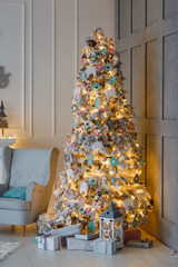 Christmas tree with presents and lights reflecting in modern scandinavian home