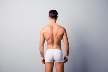 Back view photo of handsome confident guy with strong back and shoulders, wearing white underpants,...