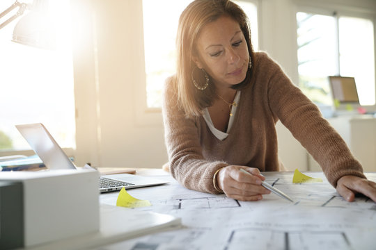 Woman architect working on blueprints in office