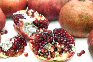 Whole and half pomegranates with ripe seeds on white background top view closeup
