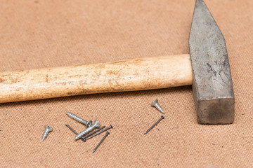Nails, screws, hammer on a wooden background