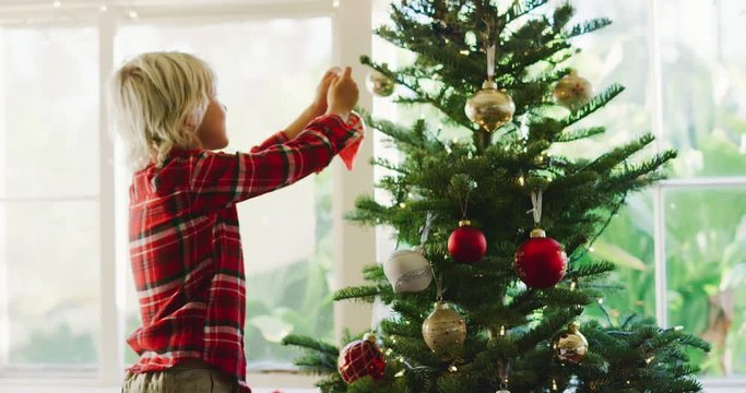 Cute young boy hanging ornaments on christmas tree