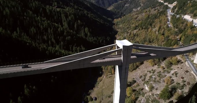 Car on a bridge, Cinema 4k aerial pan view following cars driving over a huge bridge, between mountains, on a sunny fall day, on simplon pass, in wallis, of the alps in Switzerland