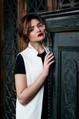 Fototapeta na wymiar Portraite of young, beautiful sad woman with short brown hair with stylish make up in black dress and white waistcoat in the studio