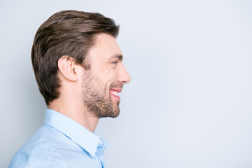 Obraz premium Close up side portrait of young, bearded, happy, smiling manager standing over grey background with copy space