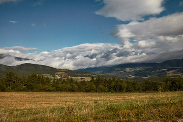 Landscape scene with dramatic white clouds rolling over hills.