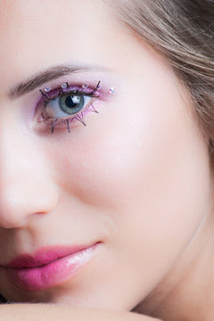 closeup of woman face with pink makeup eyelashes and crystals