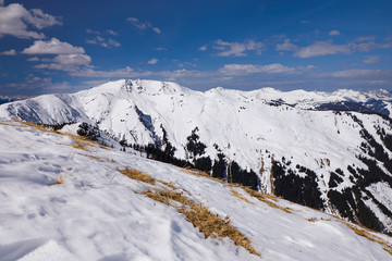 Melting ski slope snow Alps mountain view from high-altitude SCHMITTENHOHEBAHN 2000 meters peak at Zell Am See Austria Schmitten ski resort in march month
