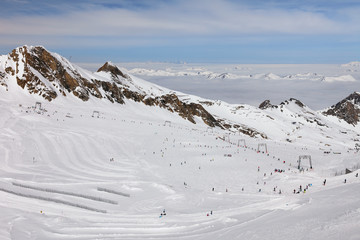 Austria, Zell Am See, Kaprun - March 21, 2017:  Highest high-altitude Kitzsteinhorn glacier ski slopes and lifts with foggy Alps Mountains, blue sky and clouds in background at Austrian ski resort