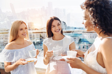 Gossip about boys. Three glad jolly female friends enjoying coffee while gossiping and laughing 