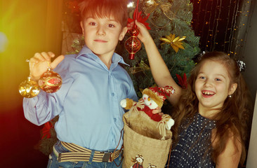 Happy little kids  decorate Christmas tree in beautiful living room with traditional fire place.