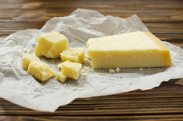 Parmesan cheese on  parchment paper on wooden background