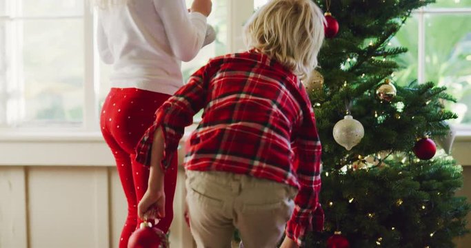 Brother and sister hanging ornaments on Christmas tree