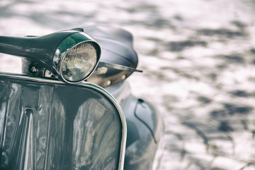 Motorradscheinwerfer im Vintage-Filmstil. Nahaufnahme eines elegant gestalteten Vintage-Rollers, der in einer Straße geparkt ist?