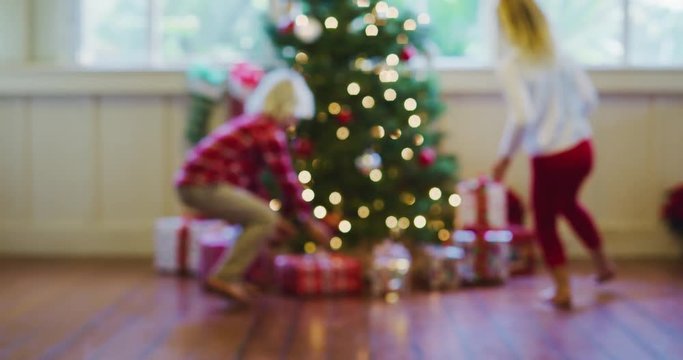 Happy young kids running to Christmas tree to open presents on Christmas morning