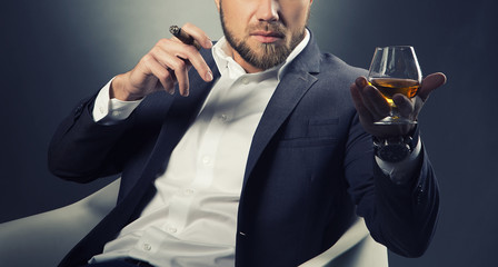 Hands of man with cognac glass and cigar