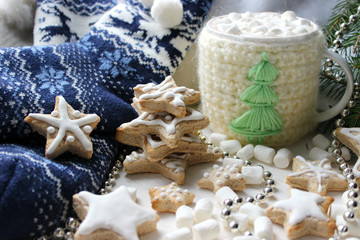 Obraz na płótnie Canvas Christmas composition. Hot cocoa with marshmallows in knitted Cup, scattered ginger cookies in glaze on a white background