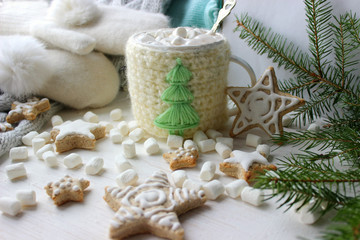 Christmas composition. Hot cocoa with marshmallows in knitted Cup, scattered ginger cookies in glaze on a white background