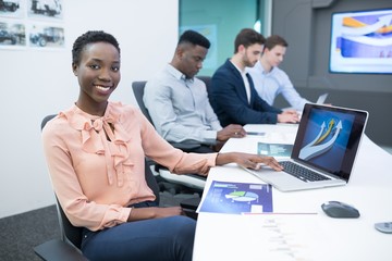 Naklejka premium Male and female executives using laptop during meeting
