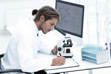 Laboratory worker sitting by table with microscope