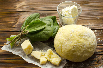 Dough, spinach,parmesan, ricotta on wooden background are ready for cooking ravioli