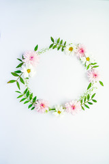 Round Frame of chamomiles, branches, leaves and lilac petals on white background. Flat lay, top view