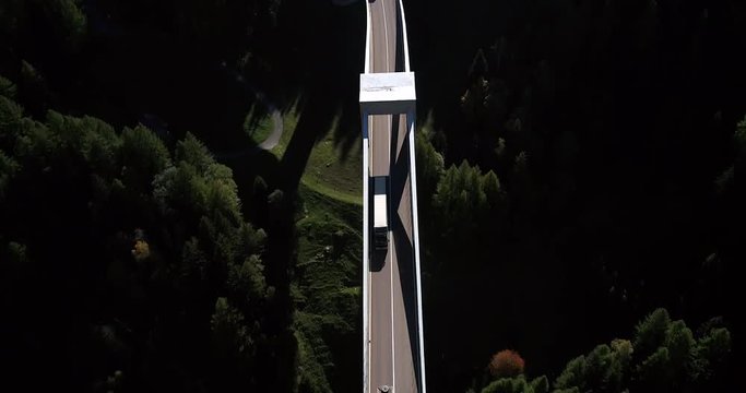 Truck on a bridge, Cinema 4k aerial tilt view following above a truck driving over a huge alpine bridge, between mountains, on a sunny fall day, on simplon pass, in wallis, of the alps in Switzerland