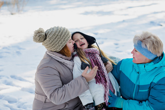 Mother, daughter, grandmother play in snow