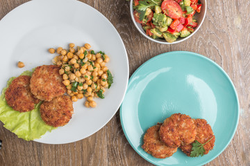 chicken cutlets with garnish of chickpeas and avakoda salad with cherry tomatoes, lemon, cilantro leaves and pepper