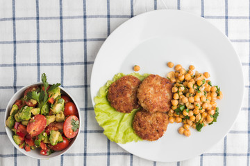 chicken cutlets with garnish of chickpeas and avakoda salad with cherry tomatoes, lemon, cilantro leaves and pepper
