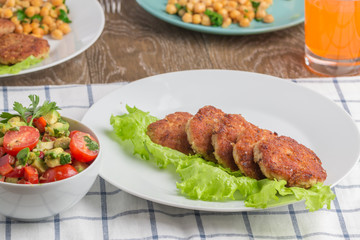 chicken cutlets with garnish of chickpeas and avakoda salad with cherry tomatoes, lemon, cilantro leaves and pepper