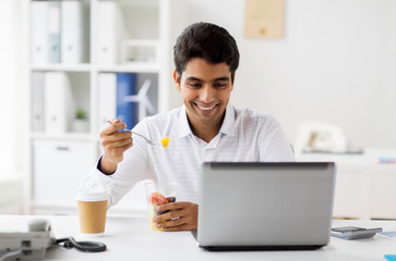 businessman with laptop eating fruits at office