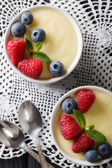 vanilla pudding decorated with raspberries and blueberries close-up. Vertical top view