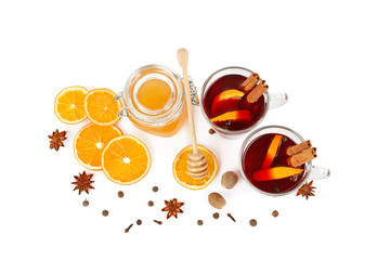 Hot red mulled wine, bee honey, slices of oranges and spices isolated on white background.