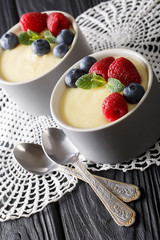vanilla pudding decorated with raspberries and blueberries close-up. vertical