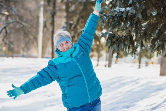 Mature active blonde woman in blue sporty jacket in winter park