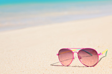 Fototapeta na wymiar Pink sunglasses on sandy tropical beach in summer