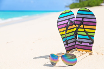Multicolored flip-flops and sunglasses on a sunny beach of Seychelles
