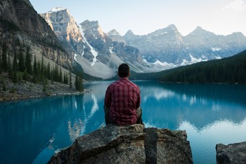Rear view of man sitting near lake side