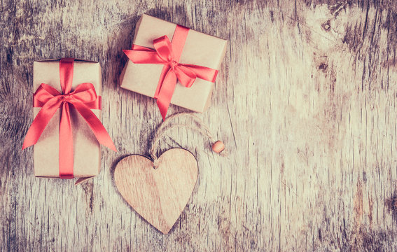 Gift box with  bow and wooden heart on an old wooden table. Copy space. Valentine's Day.