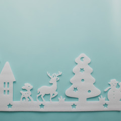 Merry Christmas and Happy New Year. Foam cutter of City with reindeers and snow boy, art and craft style on pastel color paper