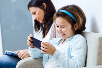 Mother and daughter using mobile phone in the waiting room of the doctor.