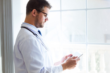 Confident male doctor using his digital tablet in the office.