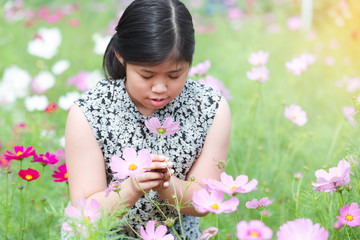 Portrait beautiful happy young girl enjoying smell in a cosmos flowering spring garden © kasipat