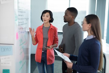 Male and female executives discussing on whiteboard